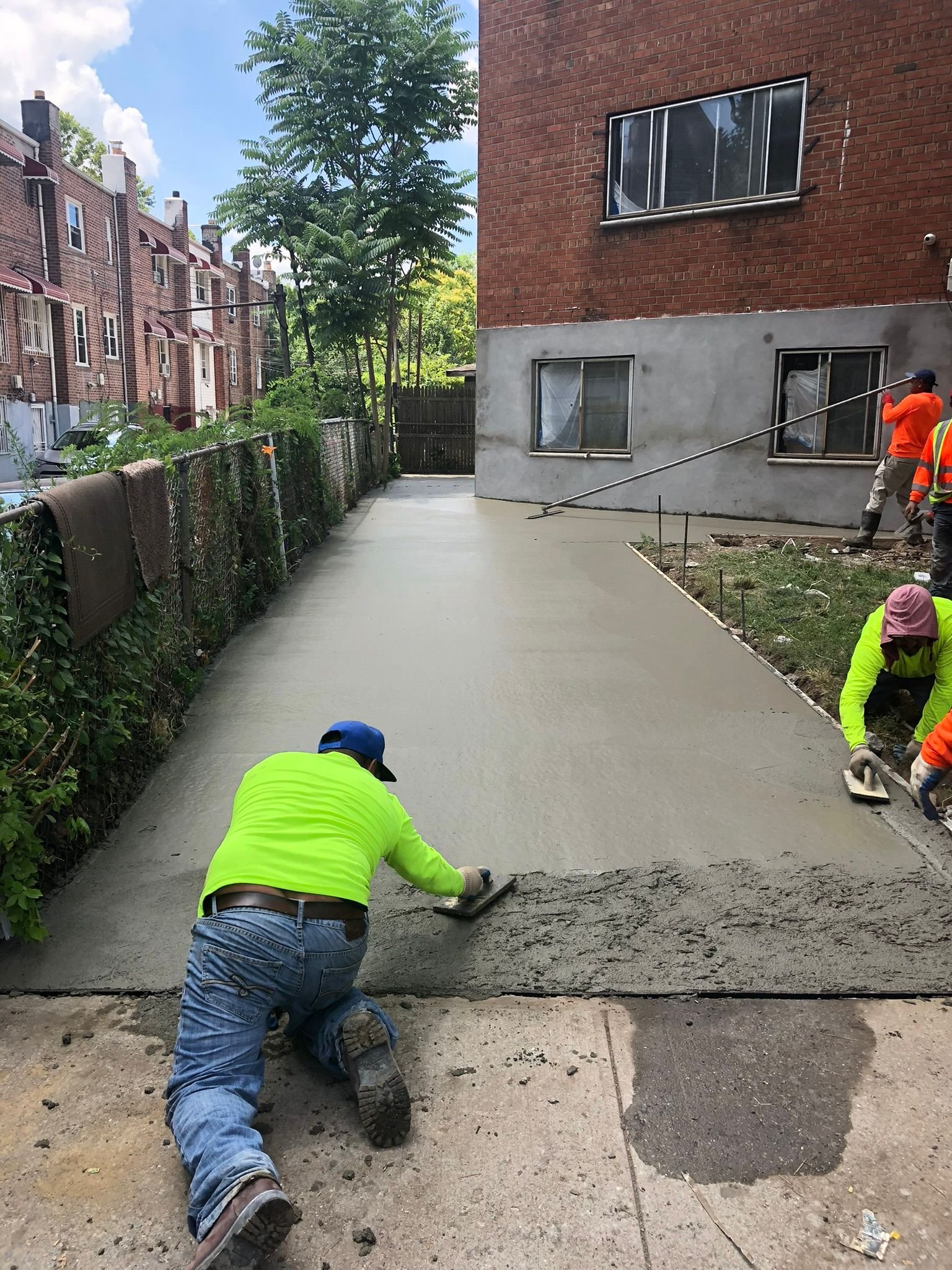 Worker smoothing and leveling fresh concrete beside a residential building during a floor leveling project in NYC.