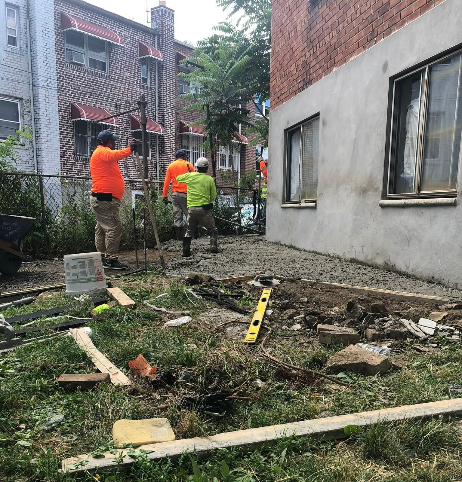 Workers preparing the ground and removing the old driveway before new concrete installation at a residential property in NYC.