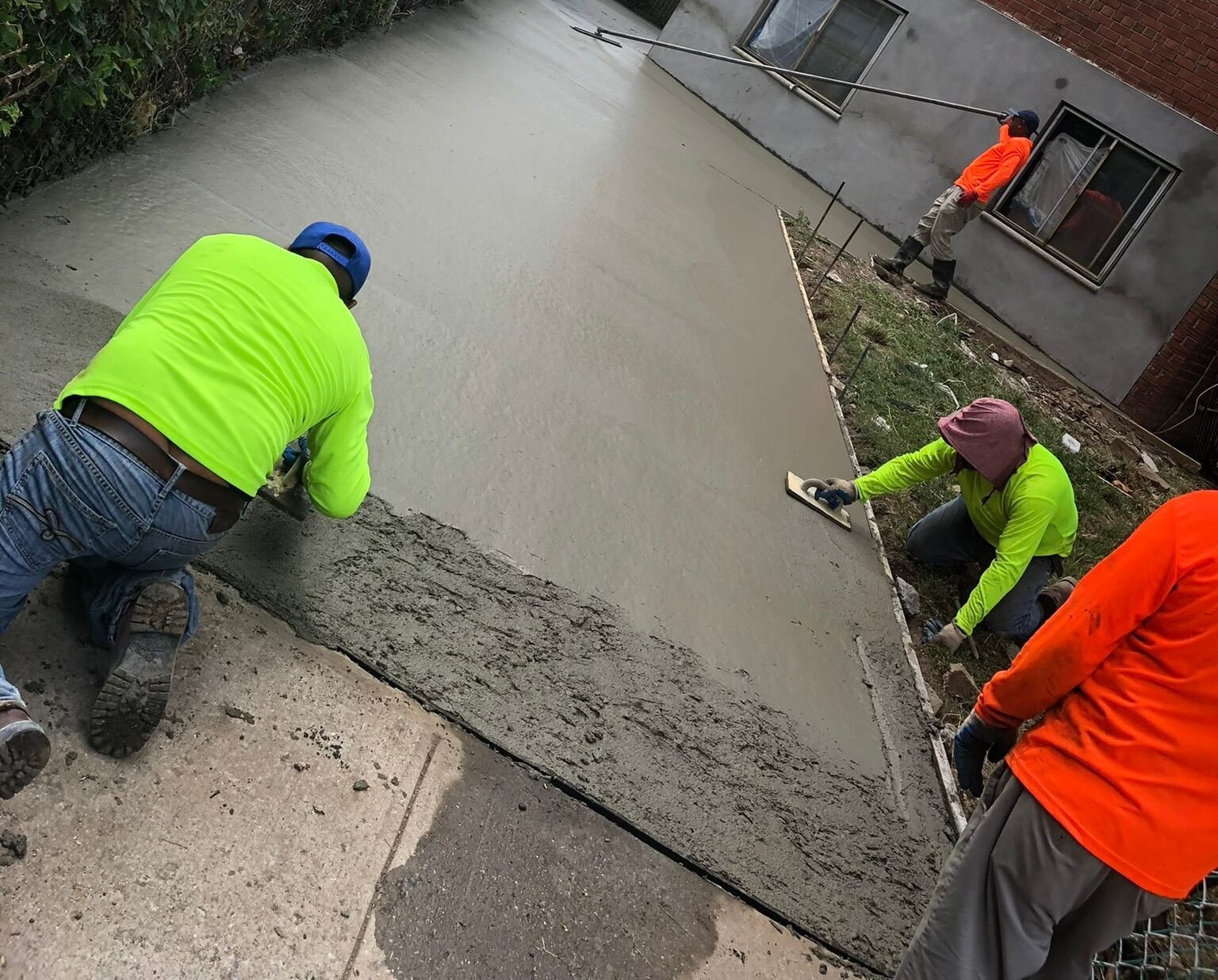 Concrete contractors expertly smoothing fresh concrete during a paving project.