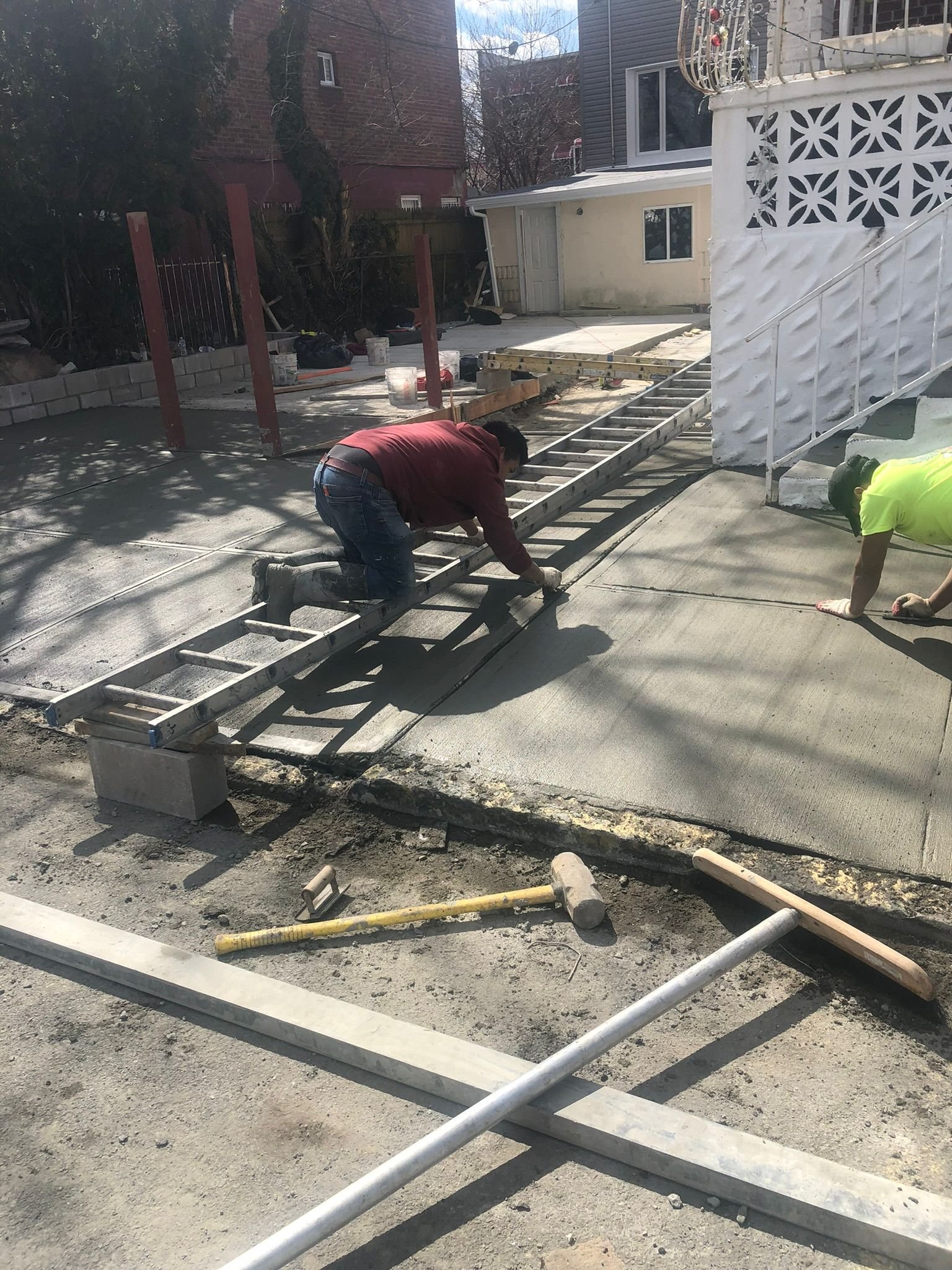 Freshly poured concrete patio being shaped and finished in a Bronx backyard.