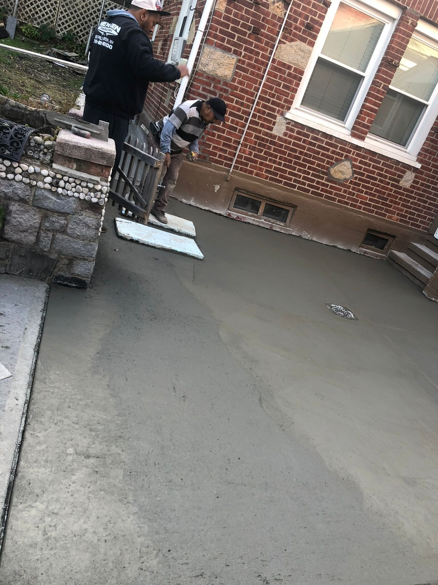 Workers performing concrete construction services such as driveways, patios, sidewalks, slabs, foundations, repairs, and leveling in New Rochelle, NY.