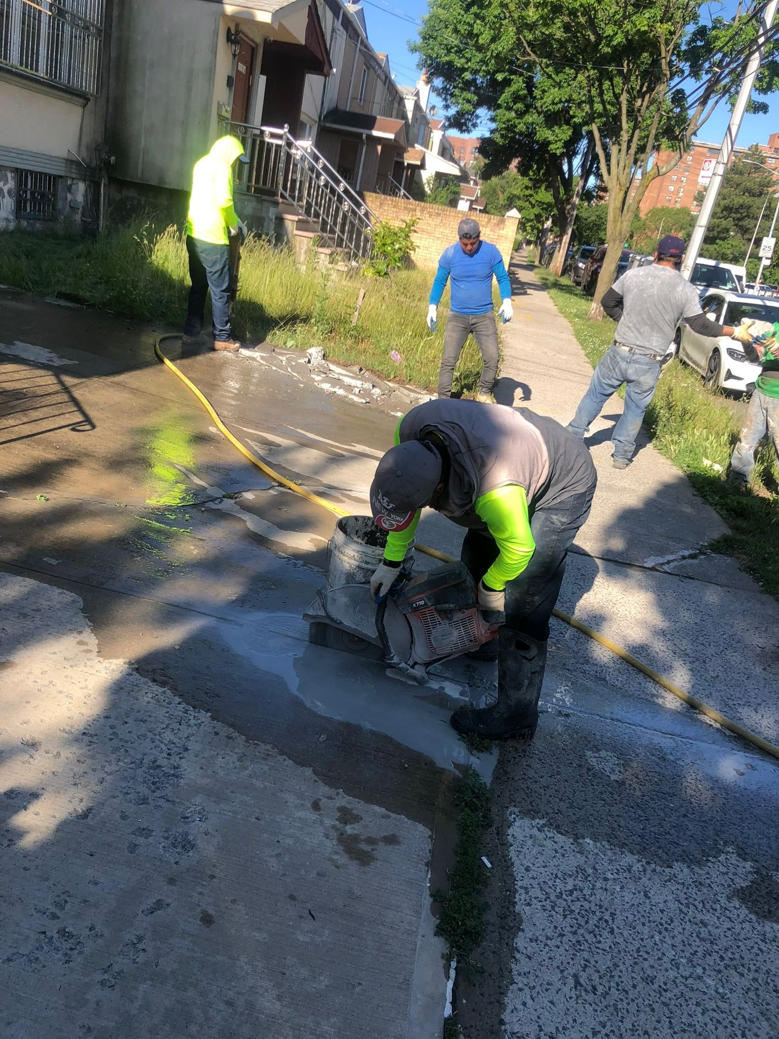 Worker patching cracks and repairing damaged concrete on a sidewalk or driveway.