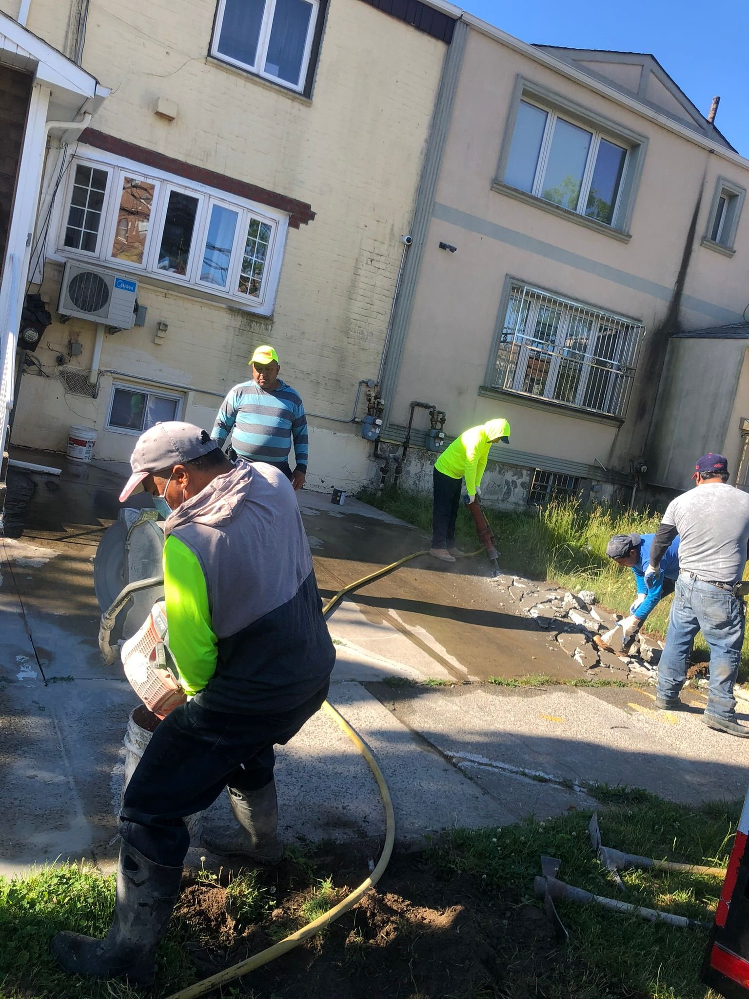 Workers patching cracks and repairing damaged concrete on a Brooklyn driveway.