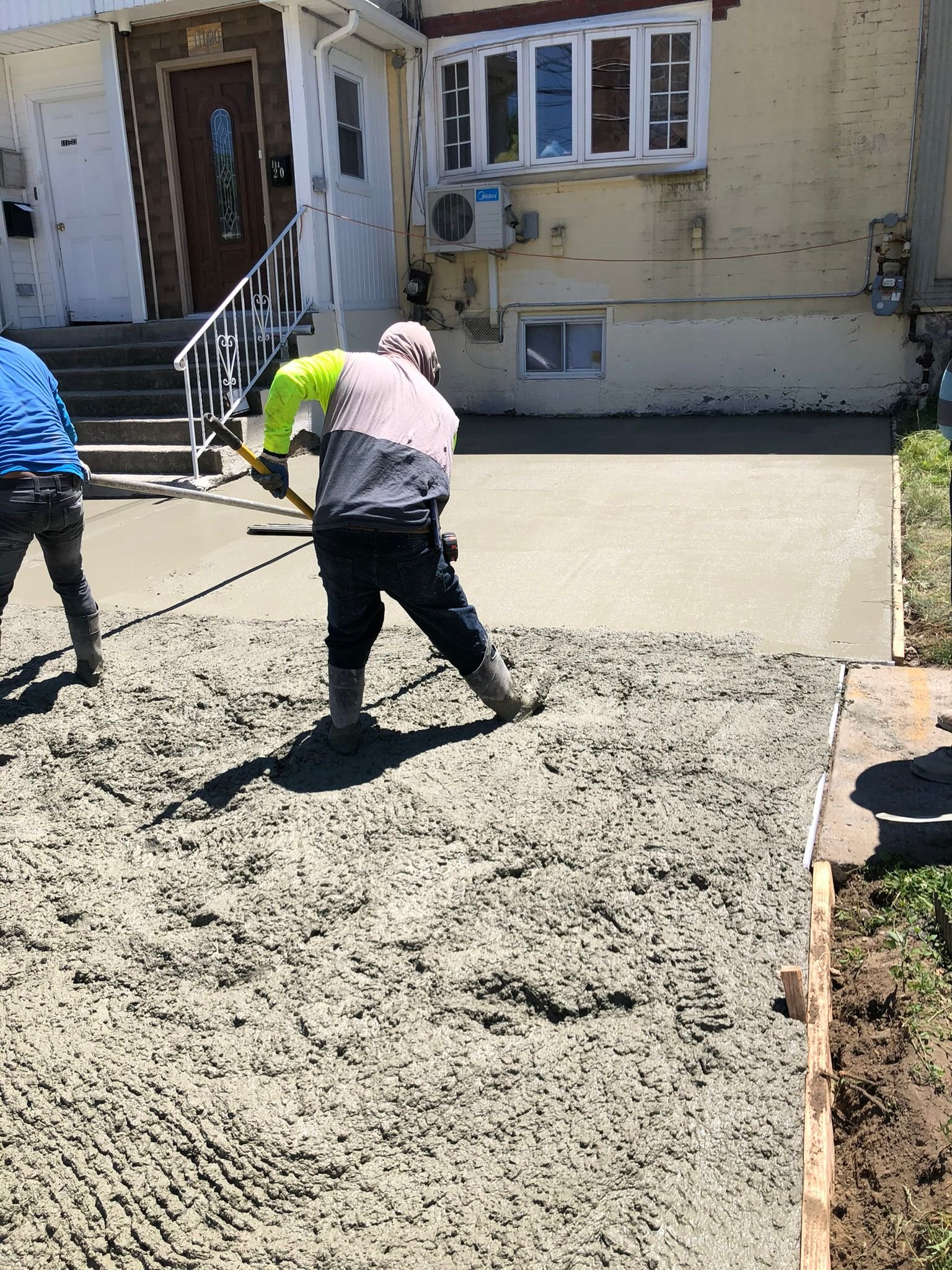 Workers installing, repairing, or finishing concrete surfaces on residential and commercial properties in New York City.