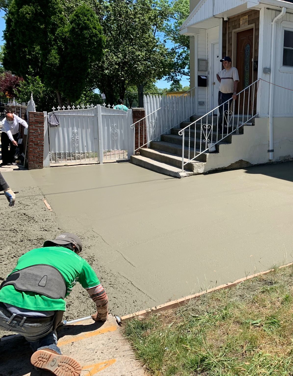 Freshly poured concrete patio being shaped and smoothed in a Brooklyn backyard.