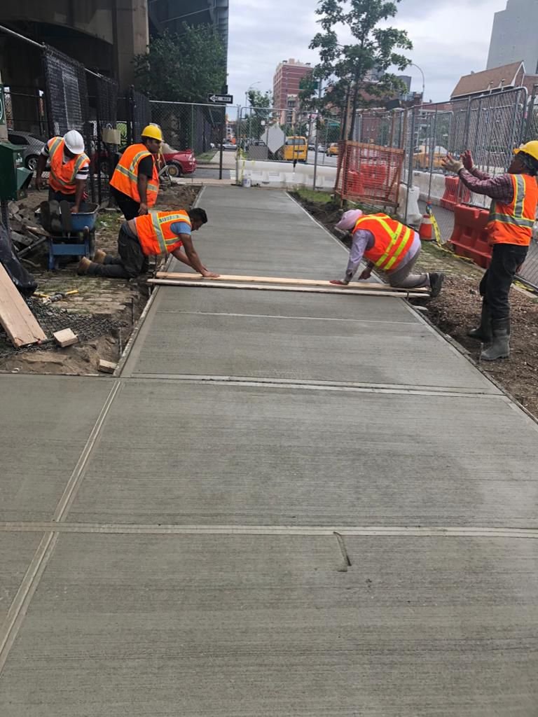 Workers performing concrete construction services such as driveways, patios, sidewalks, slabs, foundations, repairs, and leveling in New Rochelle, NY.