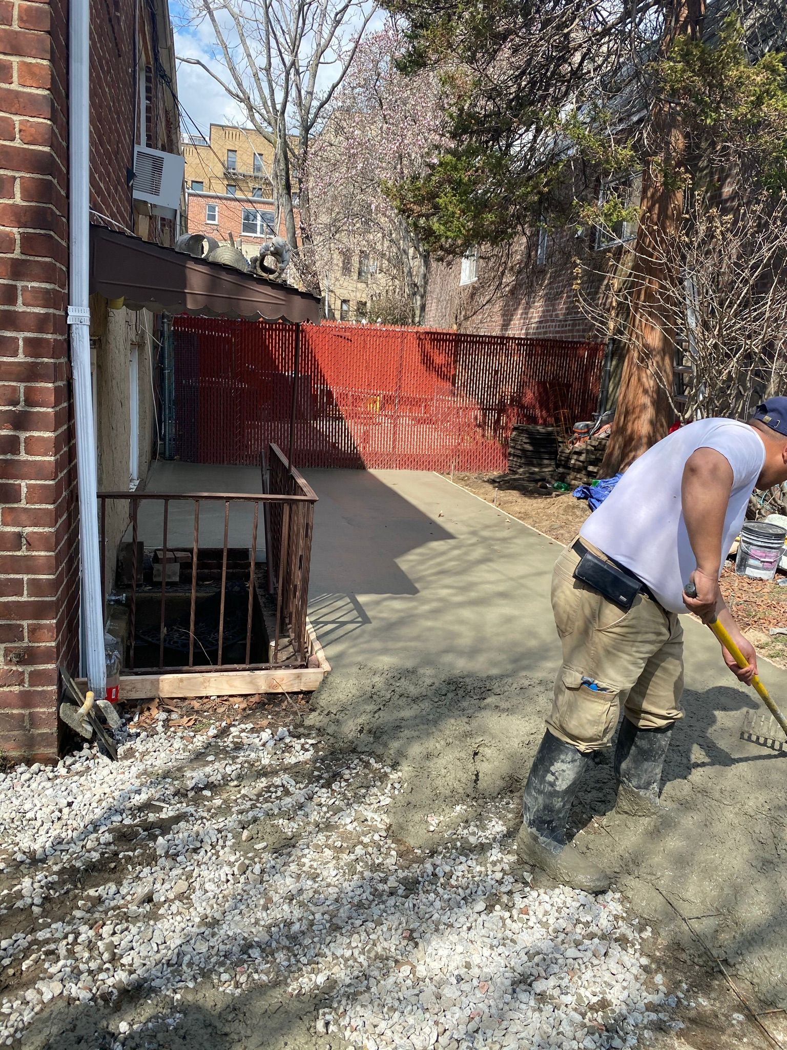 Workers pouring and leveling a concrete slab for a garage or shed in Brooklyn.