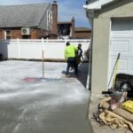 Contractor applying concrete sealant to protect a walkway in a Brooklyn neighborhood.