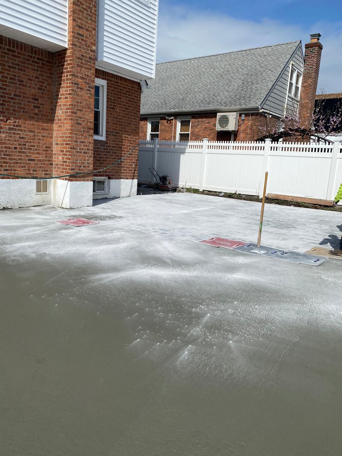 Worker leveling uneven concrete flooring inside a Brooklyn home or basement.