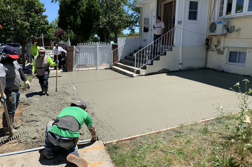 Crew finishing a poured concrete driveway at a NYC home